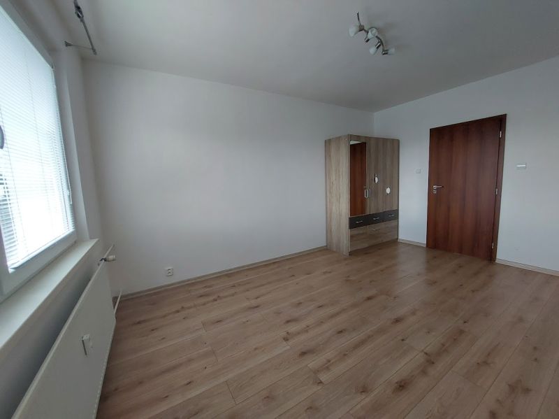A room in a 3-room apartment with a wooden decor floor and a wardrobe.