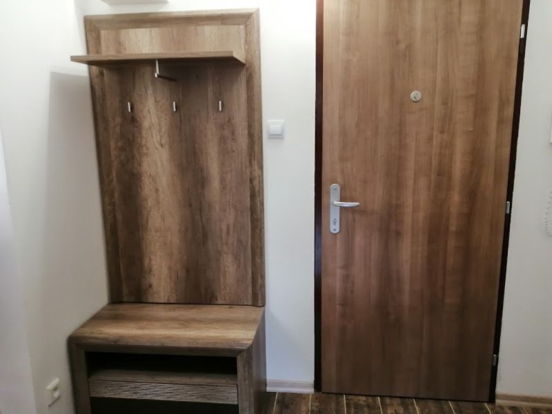 In the entrance hallway of the 3-room apartment, there are doors and a coat rack wall with a wooden decor.