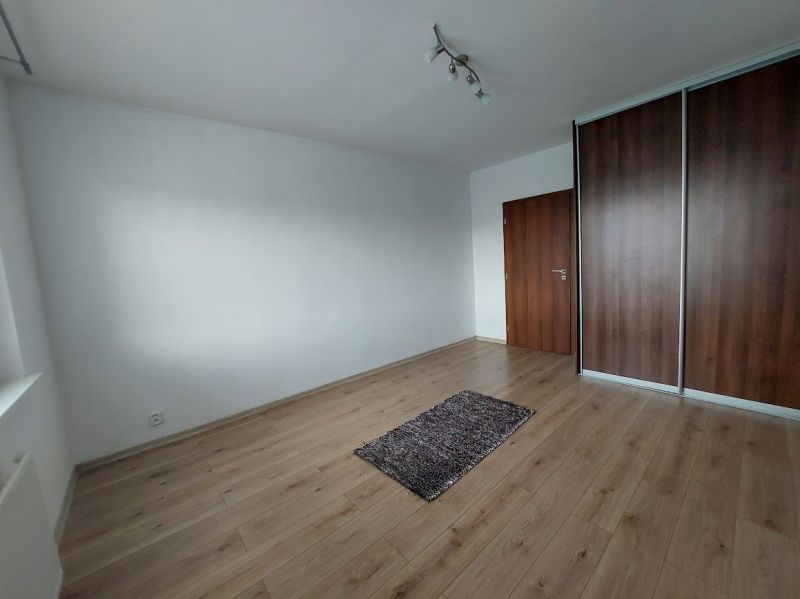 An empty room in a 3-room apartment with a wooden decor floor and a built-in wardrobe.