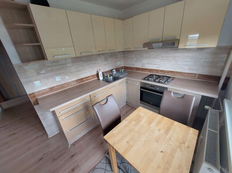 A kitchen in a 3-room apartment with a kitchen unit and a floor with a wooden decor.