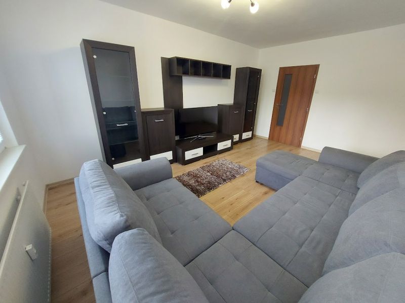 Living room in a 3-room apartment with a gray sofa and a floor with a wood decor.