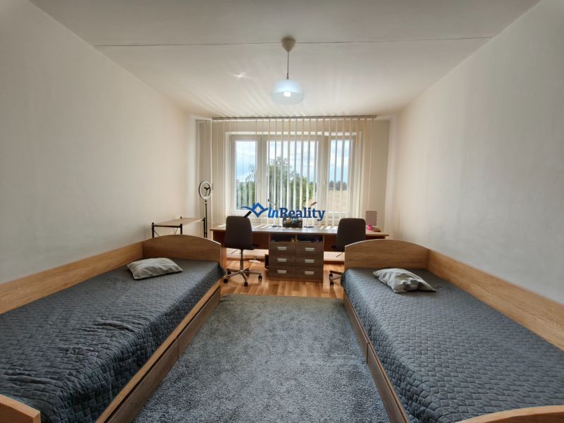 A room in a 3-room apartment with two beds, a table, and a floor with a wooden decor.