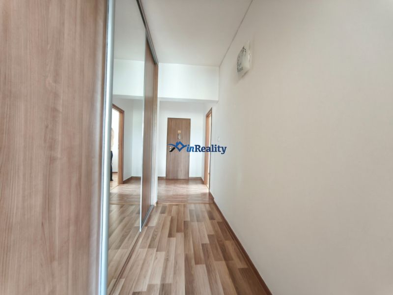 A hallway in a 3-room apartment with a wooden decor floor and a mirrored wardrobe.