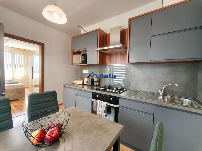 A kitchen in a 3-room apartment with a dining table and a modern kitchen unit.