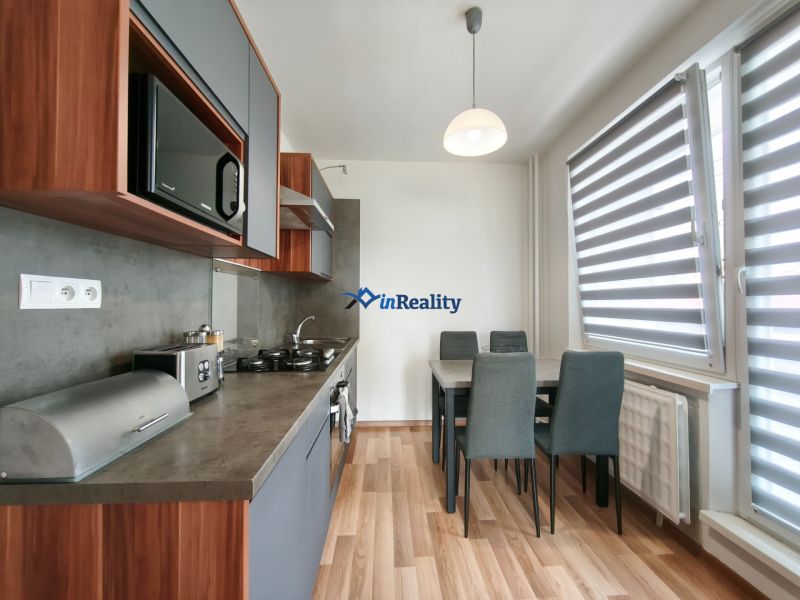 A kitchen with a table and a wooden decor floor in a 3-room apartment.