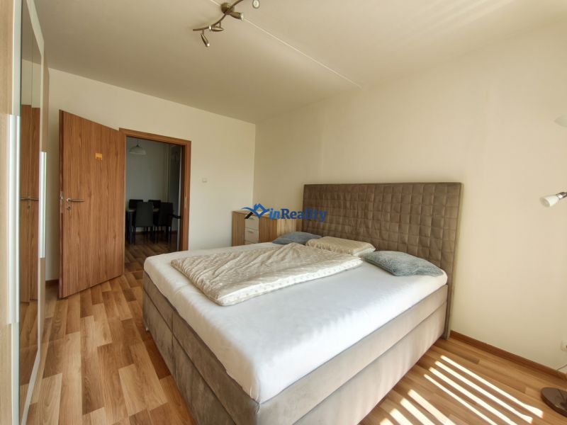 A bedroom with a bed and wooden decor flooring in a 3-room apartment.
