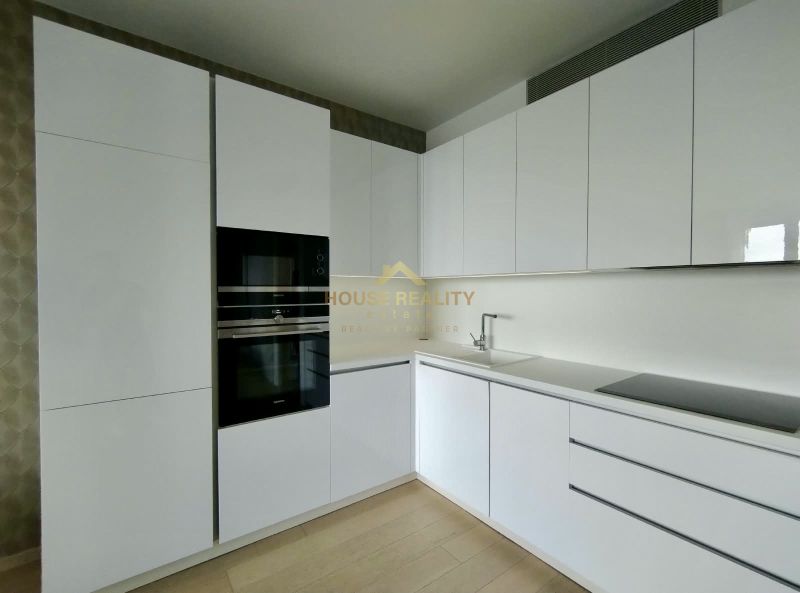 A kitchen with built-in appliances and a wooden decor floor in a 2-room apartment.