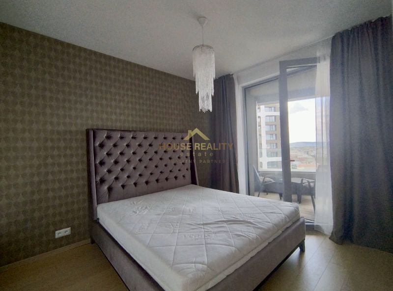 Bedroom in a 2-room apartment with a large bed, decorative curtain, and chandeliers.