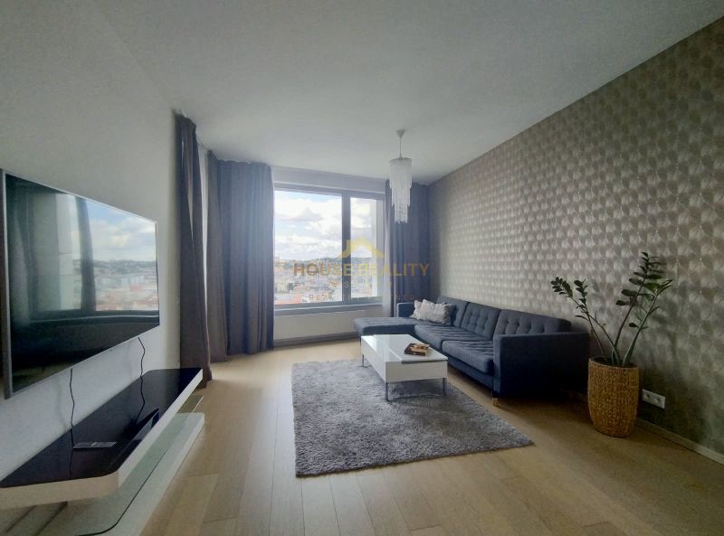 Living room in a two-room apartment with a sofa, television, and a large window.