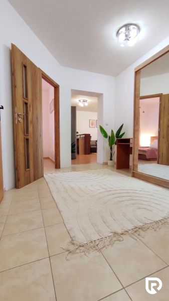 Entrance hall of a 2-room apartment with a large mirror and a plant, floor with wood decor.