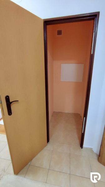 An open door compartment in a 2-room apartment with ceramic tiles on the floor.