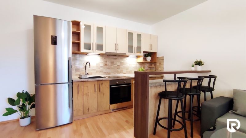 A kitchen in a 2-room apartment with a wooden decor floor and a bar counter.