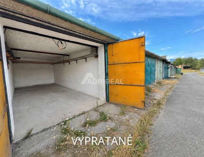 Open garages in Detva with an asphalt access road and blue sky.