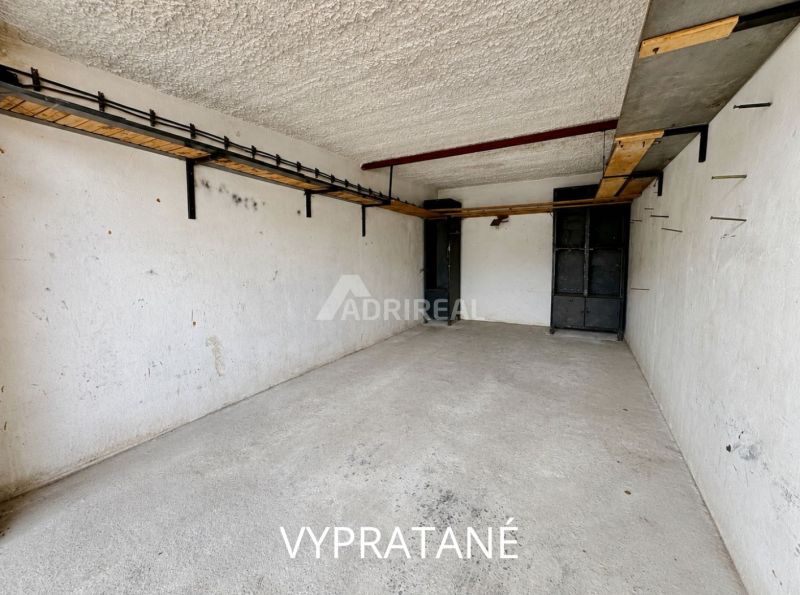 Empty garages in Detva with shelves on the wall and a concrete floor.