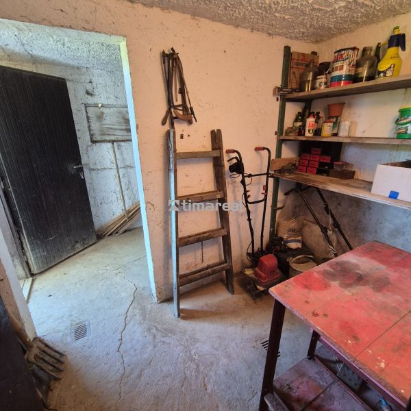 The interior of a cabin with stacked shelves, a table, and a ladder in the workshop.