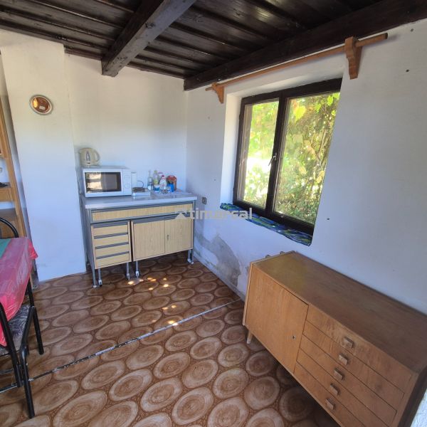 Interior of a cabin with a window, kitchen counter, and floor with wood decor.
