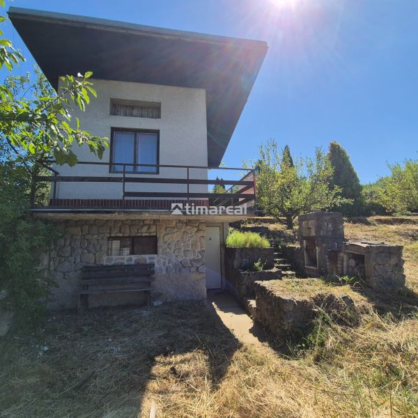 A cottage in Myjava with a stone facade, surrounded by lush greenery and an outdoor fireplace.