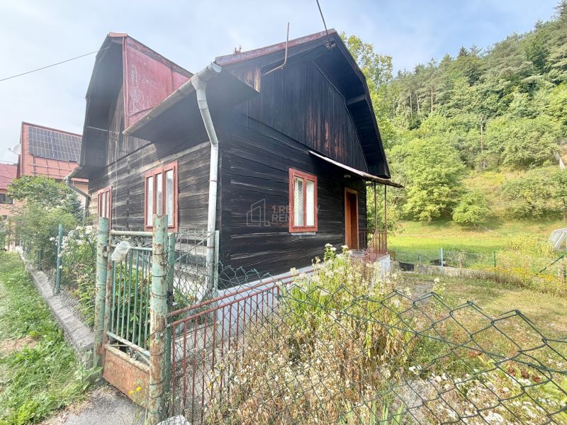 A family house on Ochodnica Street in Ochodnica surrounded by greenery and an older fence.
