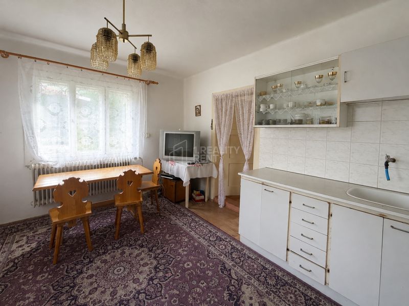 Interior of a family house with a dining area, kitchen unit, television, and table with a wooden decor.