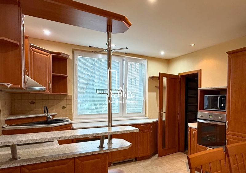 A kitchen in a 3-room apartment with wooden cabinets and tiled flooring.