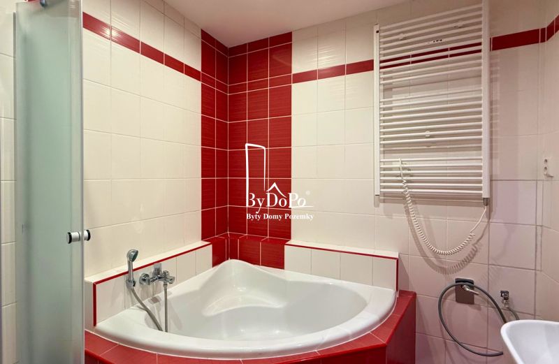 A bathroom in a 3-room apartment with a corner bathtub and red tiles.