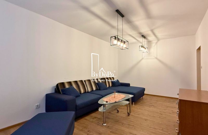 Living room with a blue sofa, glass table, and wood-patterned flooring.