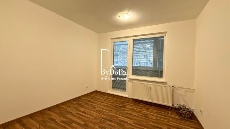 A room in a 3-room apartment with a wooden decor floor and a window with blinds.
