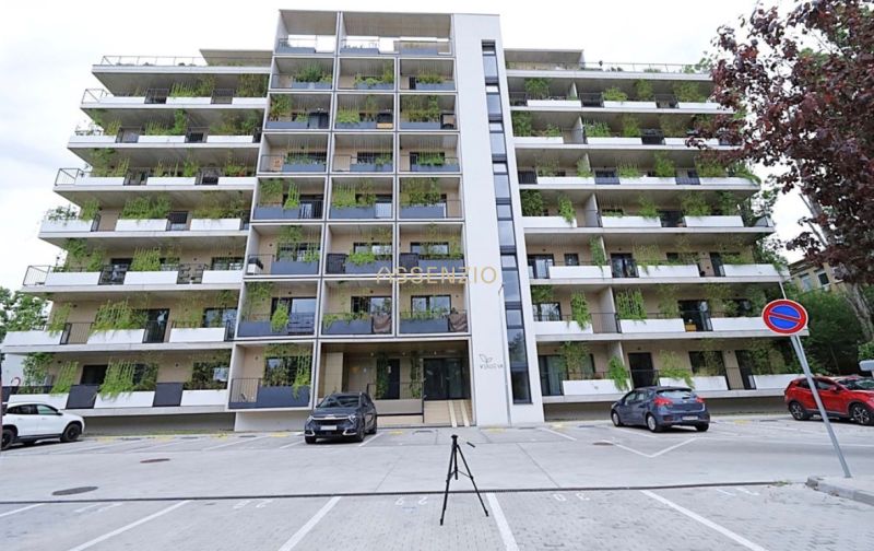 Apartment building in Bratislava-Rača with greenery on balconies and parking spaces.