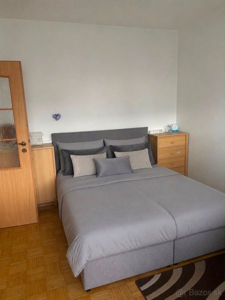 A bedroom with a bed and a wooden decor floor in a three-room apartment.
