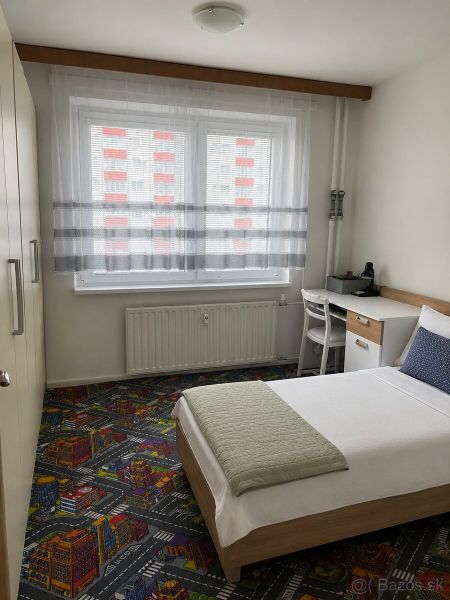 Single bed in a 3-room apartment with a creative carpet and a work desk.