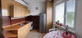 A kitchen in a 3-room apartment with a kitchen unit, a gas stove, and a floor with a wooden decor.
