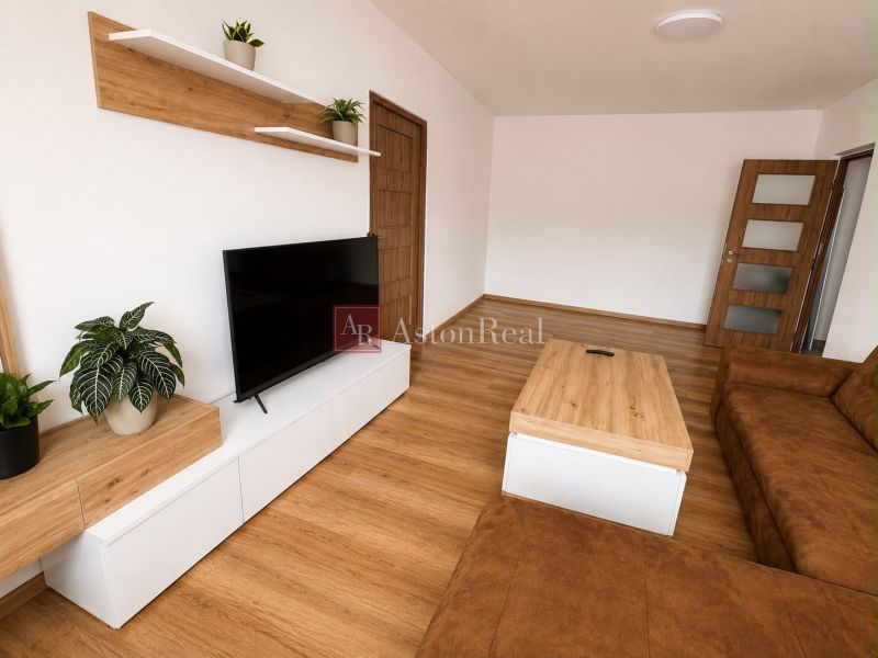 Living room in a two-room apartment with a wooden decor floor and a comfortable sofa.
