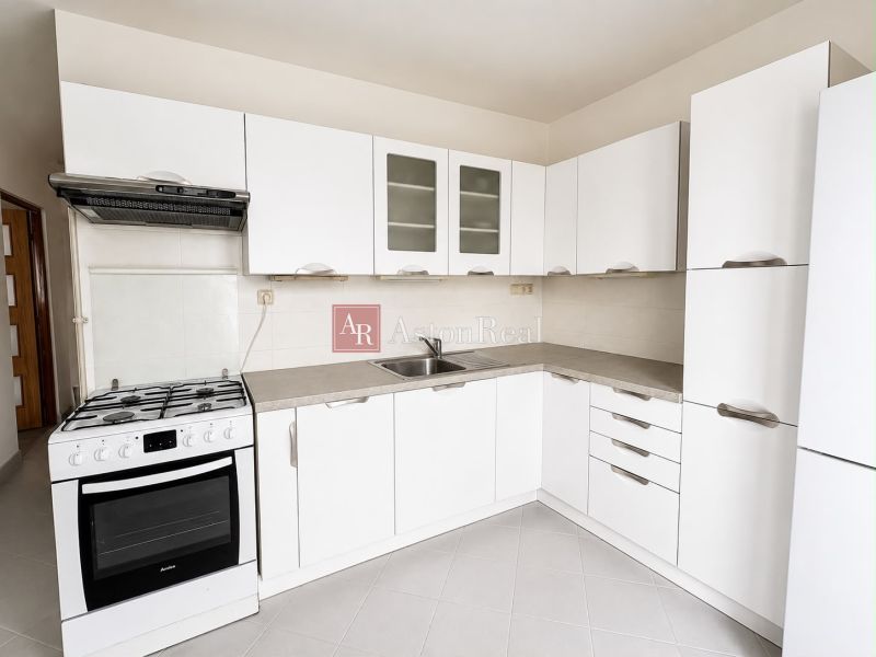 A white kitchen with a gas stove and white cabinets in a two-room apartment.
