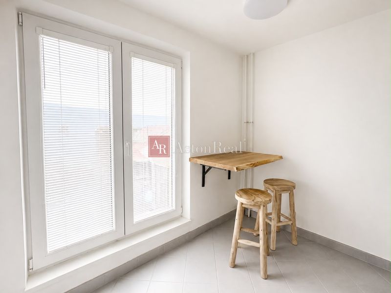 Simple kitchen area with wooden decor and a large window in a two-room apartment.