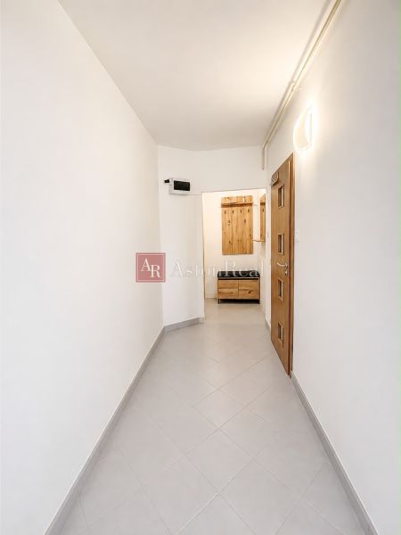 A hallway in a 2-room apartment with light tiles and wooden doors.
