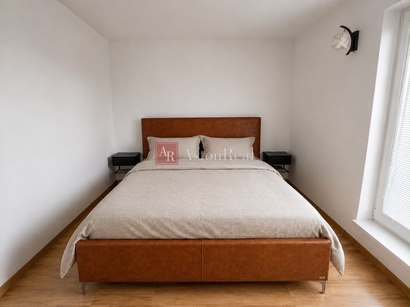 A bedroom in a two-room apartment with a bed and a wooden decor floor.