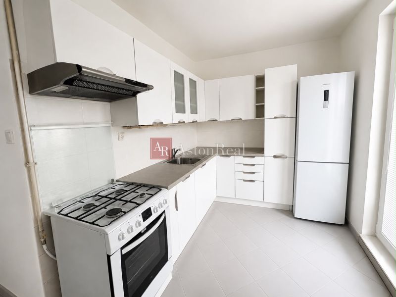 A kitchen in a 2-room apartment with white cabinets and a gas stove.