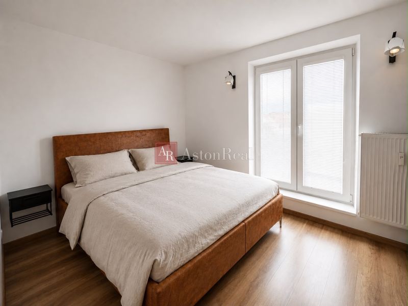 A bright bedroom with a double bed and a wooden decor floor in a 2-room apartment.