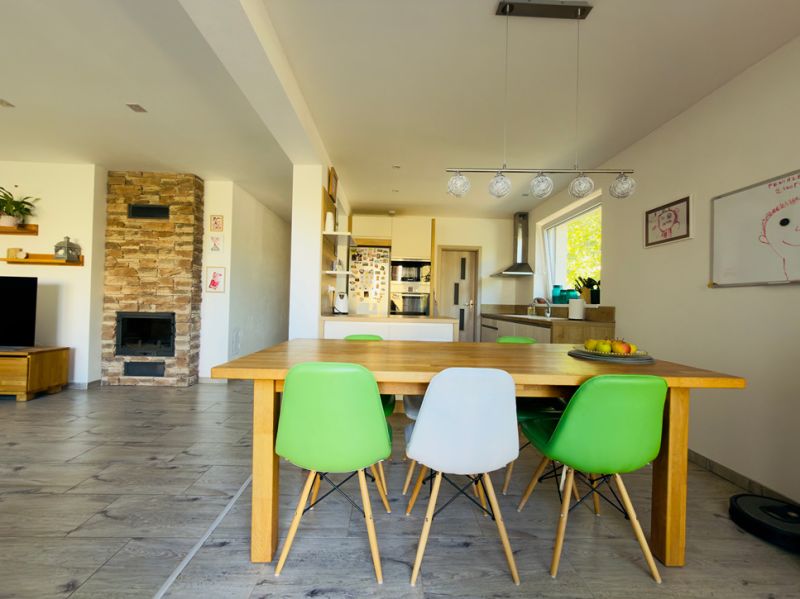 Dining table with colorful chairs and a fireplace in a family house with decorative flooring.