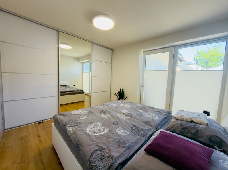 Bedroom in a family house with a bed, built-in wardrobe, and wooden decor flooring.