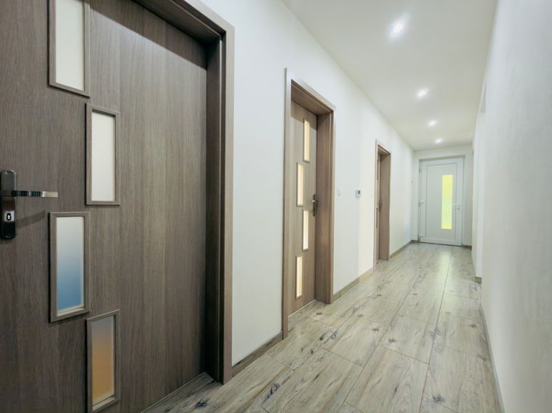 A hallway of a family house with a wooden decor floor and wooden doors.