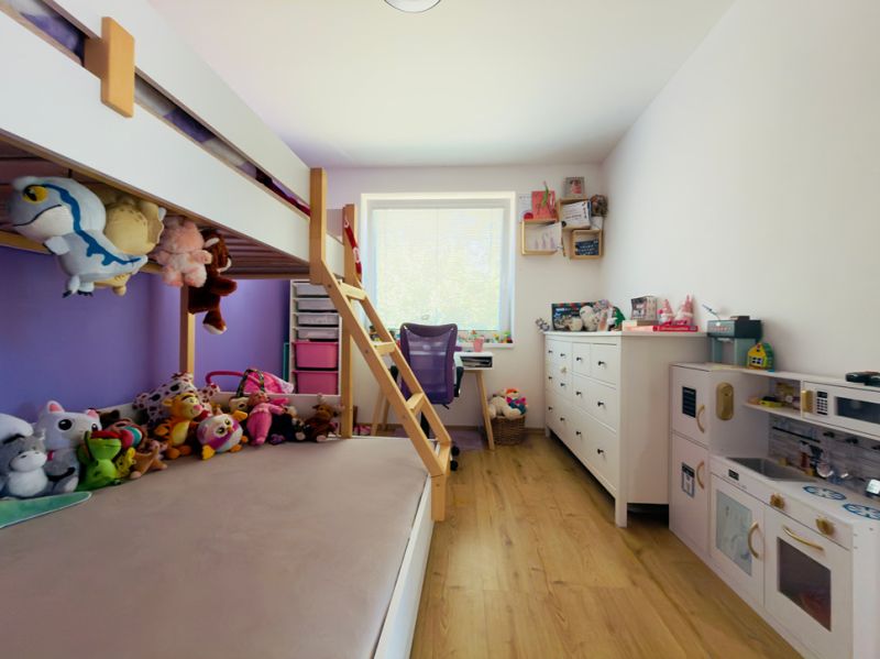 Children's room in a family house with a bunk bed, toys, and a wooden decor floor.