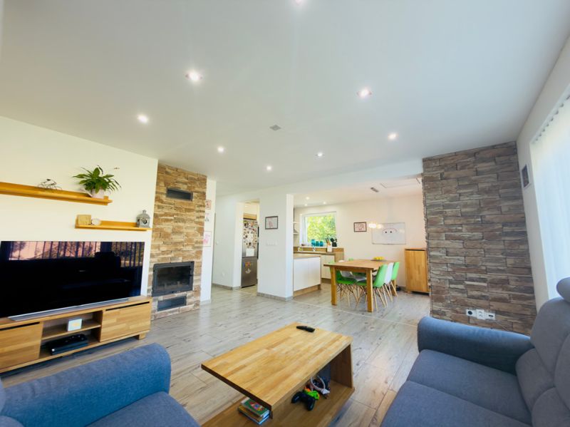 Living room in a family house with a wood-patterned floor, fireplace, and television.