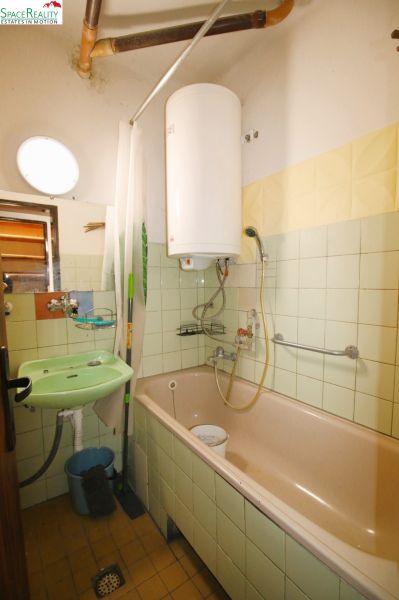 Bathroom in a 3-room apartment with a bathtub, sink, and boiler.