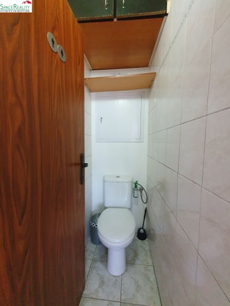 Bathroom in a 3-room apartment with tiles and storage space above the toilet.