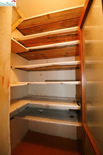 A pantry in a 3-room apartment with wooden shelves and glass doors.