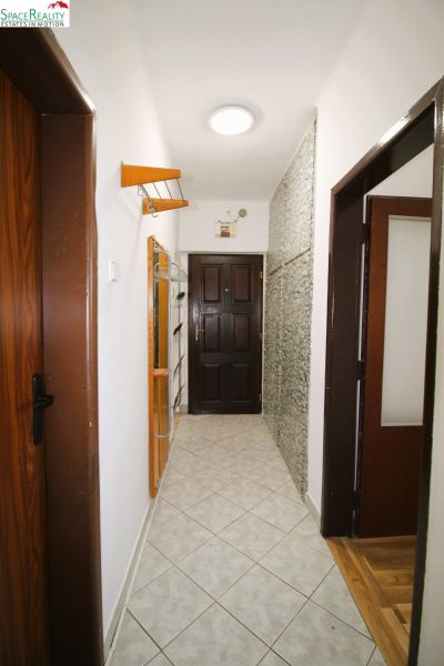 A hallway with a coat rack, mirror, and tiles in a 3-room apartment.