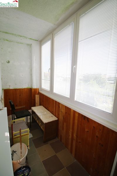 Glazed loggia in a 3-room apartment with wooden paneling and tiles.