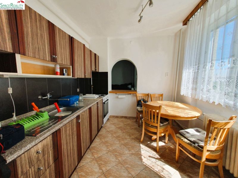 A kitchen with patterned cabinets, a dining table, and a large window, a 3-room apartment.