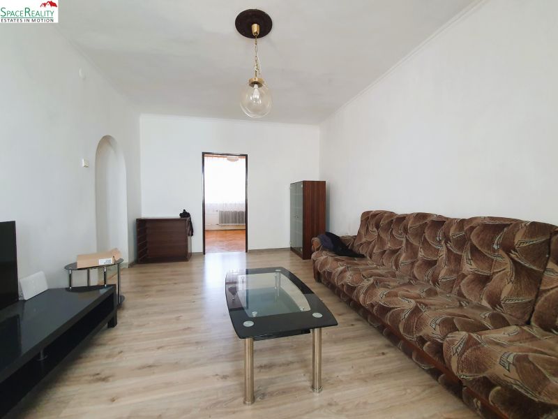 Living room in a 3-room apartment with a wooden decor floor and a brown sofa.